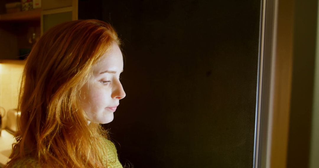 Thoughtful Woman with Red Hair Looking Out a Window - Free Images, Stock Photos and Pictures on Pikwizard.com