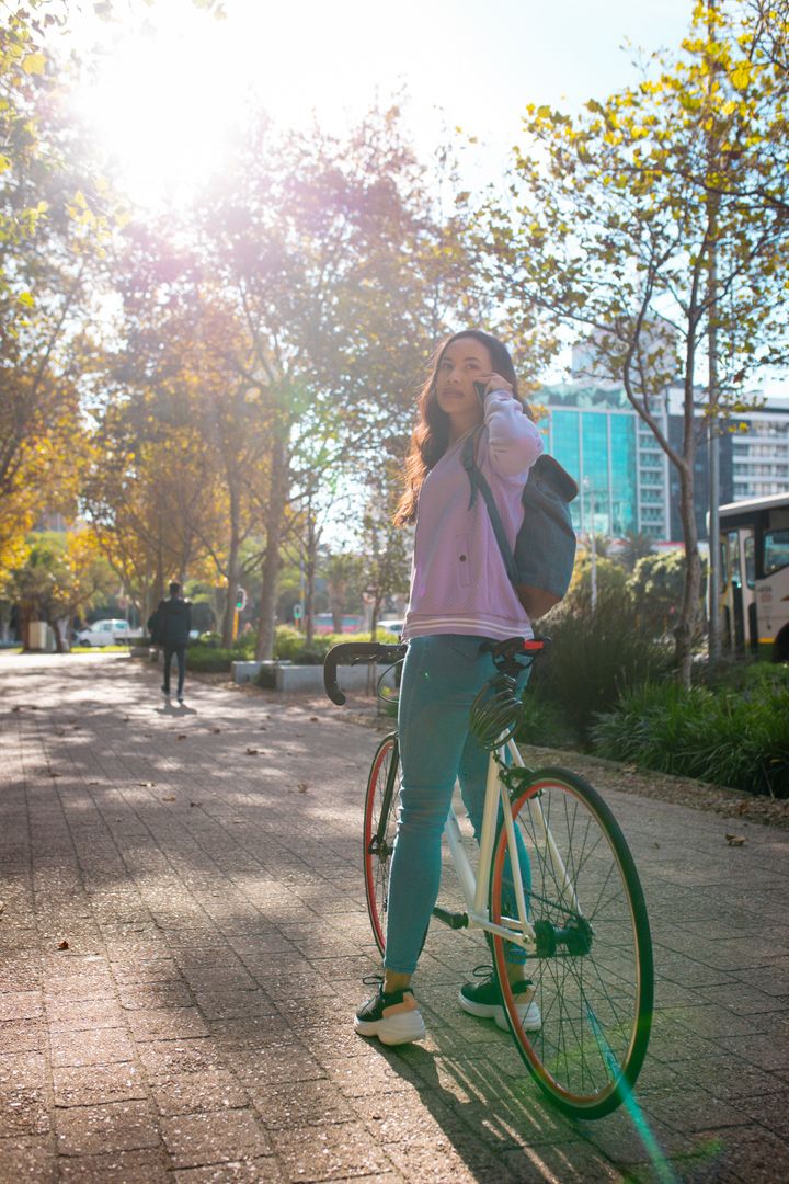 Smiling asian woman wearing backpack, using smartphone, standing with bike in street - Free Images, Stock Photos and Pictures on Pikwizard.com