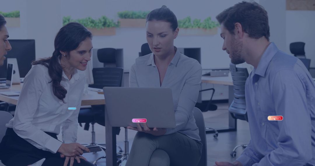 Team Collaborating Around Laptop Brainstorming in Modern Open-Plan Office with Greenery