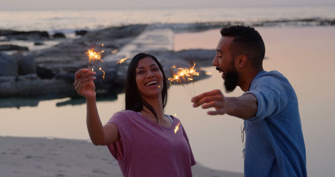 Happy Couple Holding Sparklers at Beach Sunset - Free Images, Stock Photos and Pictures on Pikwizard.com