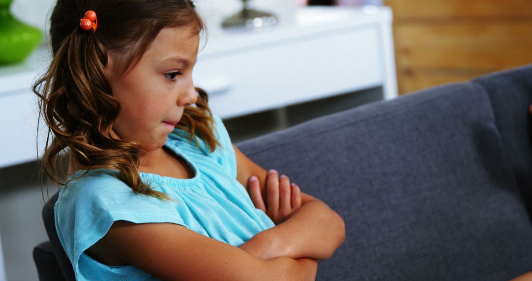 Pensive Young Girl Sitting on Couch with Arms Crossed - Free Images, Stock Photos and Pictures on Pikwizard.com