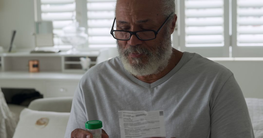 Senior biracial man examines medication at home - Free Images, Stock Photos and Pictures on Pikwizard.com