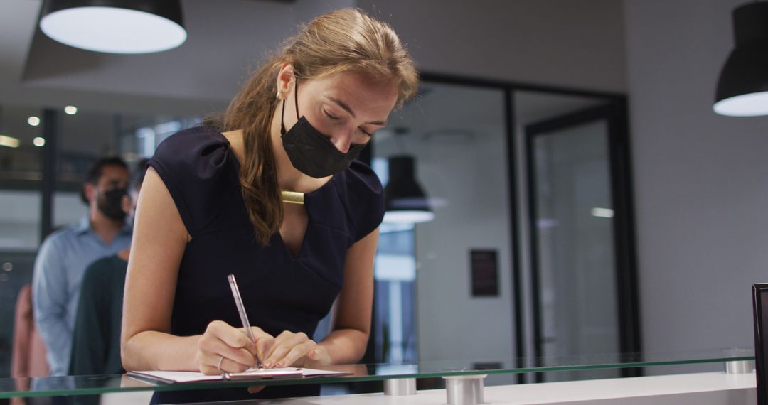 Woman Wearing Mask Signing Document at Reception Desk - Free Images, Stock Photos and Pictures on Pikwizard.com