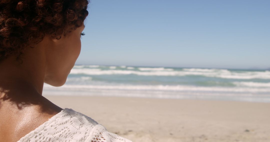 Woman Relaxing by Tranquil Ocean Beach on Sunny Day - Free Images, Stock Photos and Pictures on Pikwizard.com