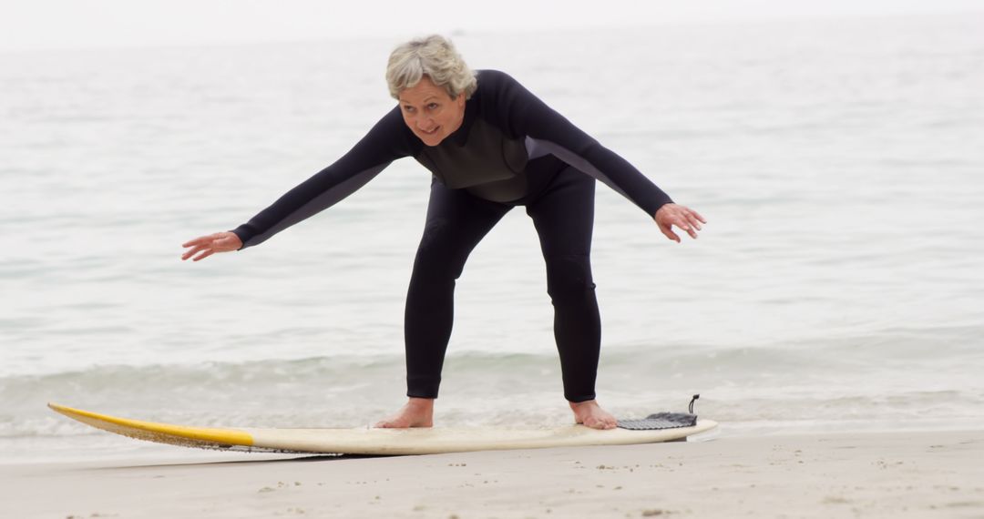 Senior Woman Practicing Surfing on Beach - Free Images, Stock Photos and Pictures on Pikwizard.com