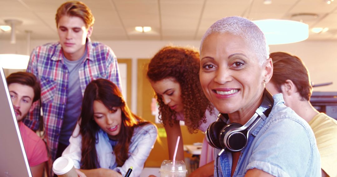 Smiling Mature Woman Collaborates with Diverse Team in Modern Office - Free Images, Stock Photos and Pictures on Pikwizard.com