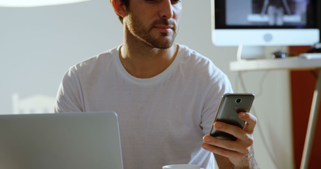 Young Man Working on Laptop and Smartphone in Home Office - Free Images, Stock Photos and Pictures on Pikwizard.com