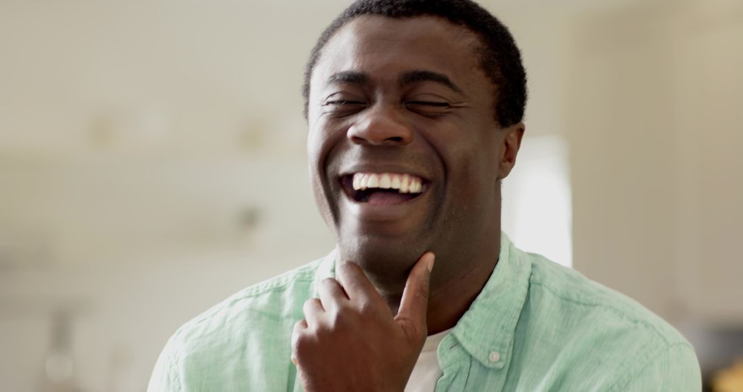 Joyful Man Wearing Green Shirt Laughing Naturally at Home