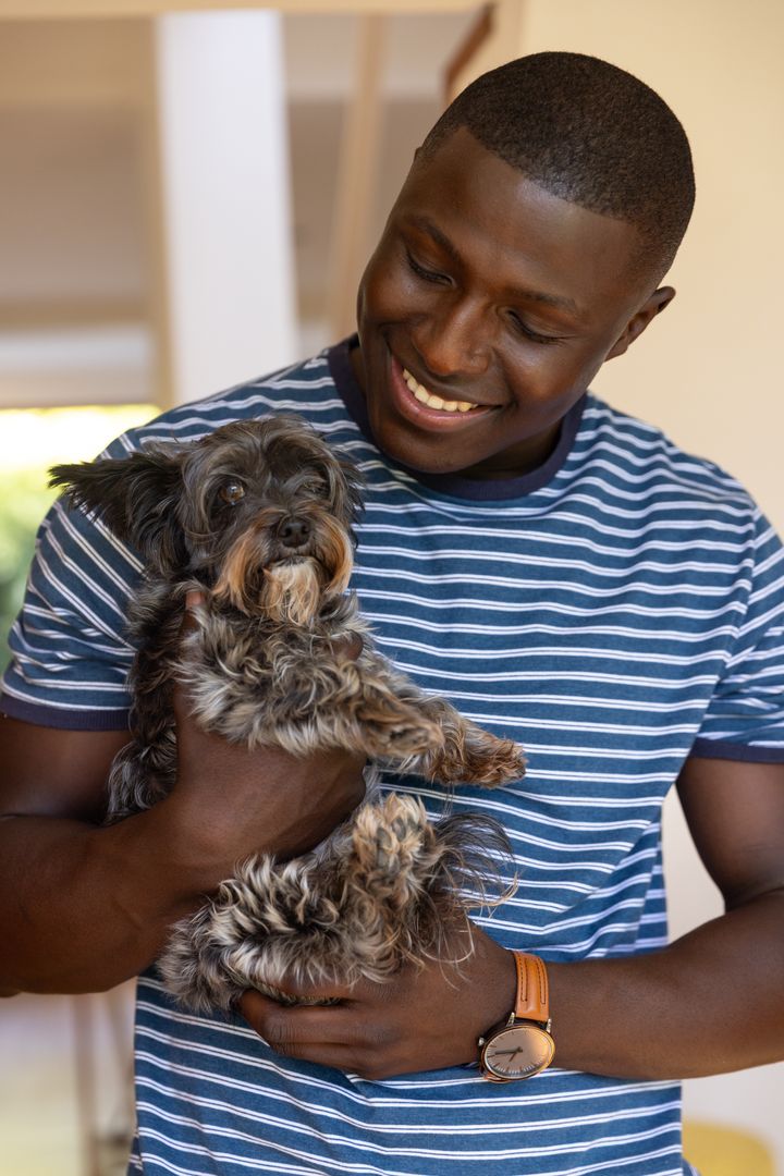 Smiling Man Holding Adorable Dog in Cozy Home Environment