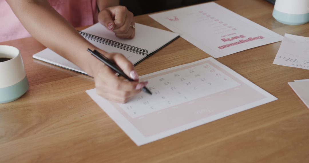 Hands Scheduling Notes on a Calendar at Wooden Desk