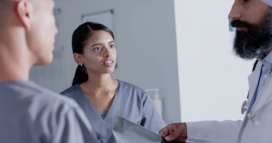 Focused Doctors Discussing X-Ray in Busy Hospital Corridor