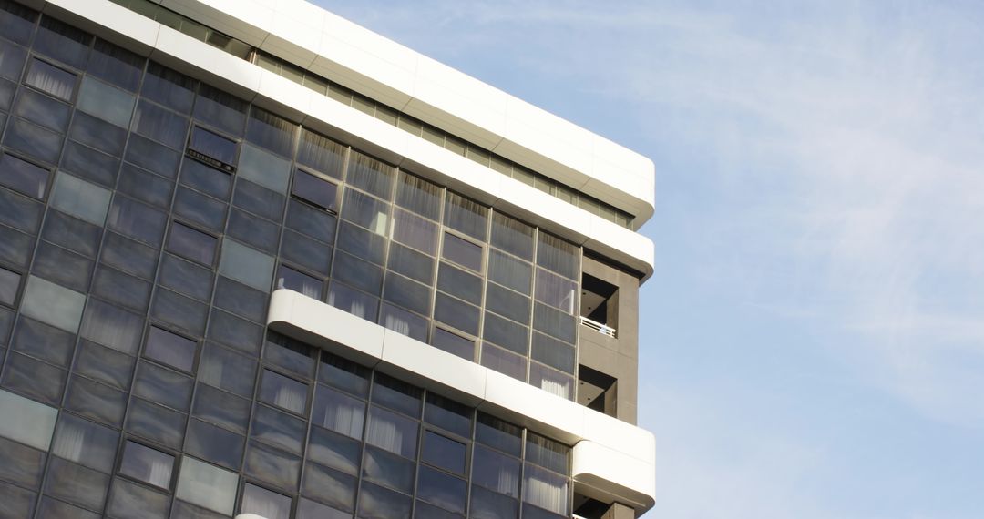 Modern office tower corner showcasing curtainwall glass grid with white ledges and balconies