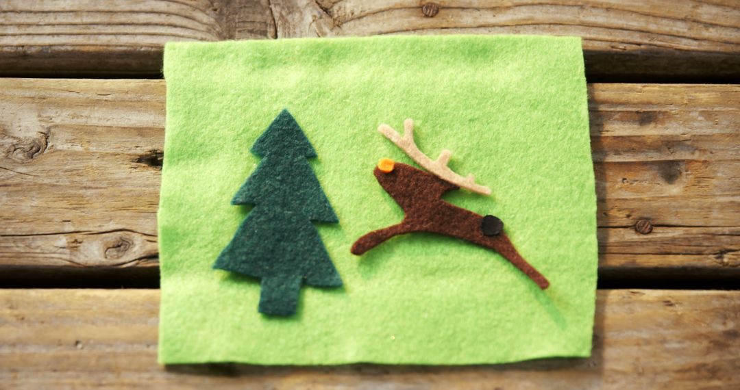 Handcrafted green felt fabric with tree and reindeer cutouts adds a cozy holiday touch. - Free Images, Stock Photos and Pictures on Pikwizard.com