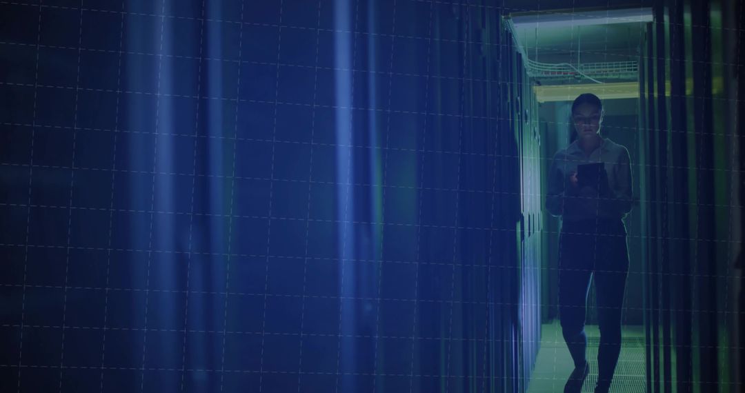 Technology Specialist Checking Tablet in Dimly Lit Datacenter Corridor