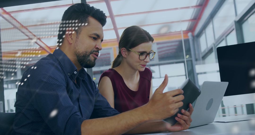 Colleagues Analyzing Data on Tablet and Laptop in Modern Office