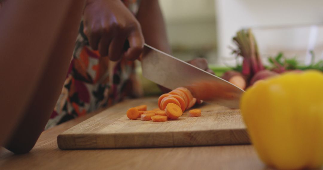 Close-Up of Person Slicing Carrots in Kitchen on Wooden Cutting Board - Free Images, Stock Photos and Pictures on Pikwizard.com