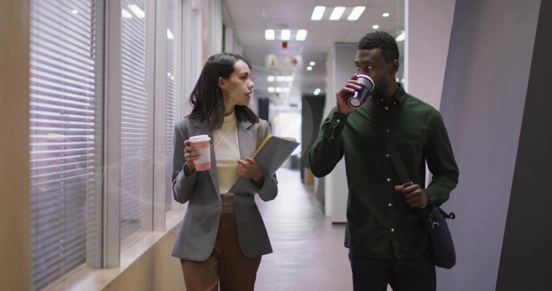 Colleagues Walking and Conversing in Office Corridor with Coffee