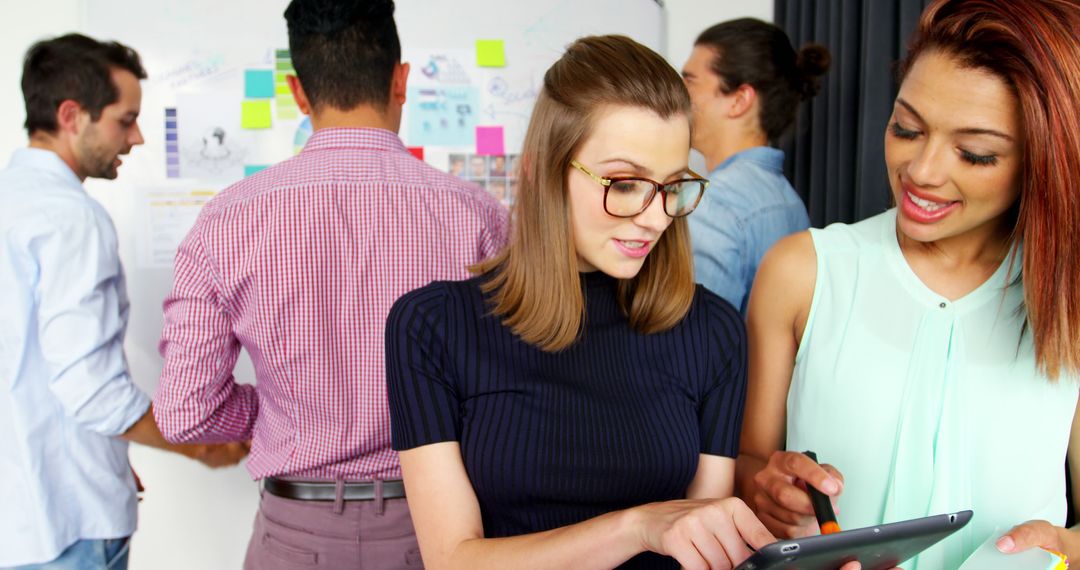 Colleagues Collaborating Over Tablet in Creative Office Space