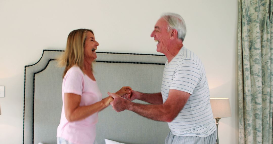 Happy Senior Couple Laughing and Dancing in Bedroom - Free Images, Stock Photos and Pictures on Pikwizard.com