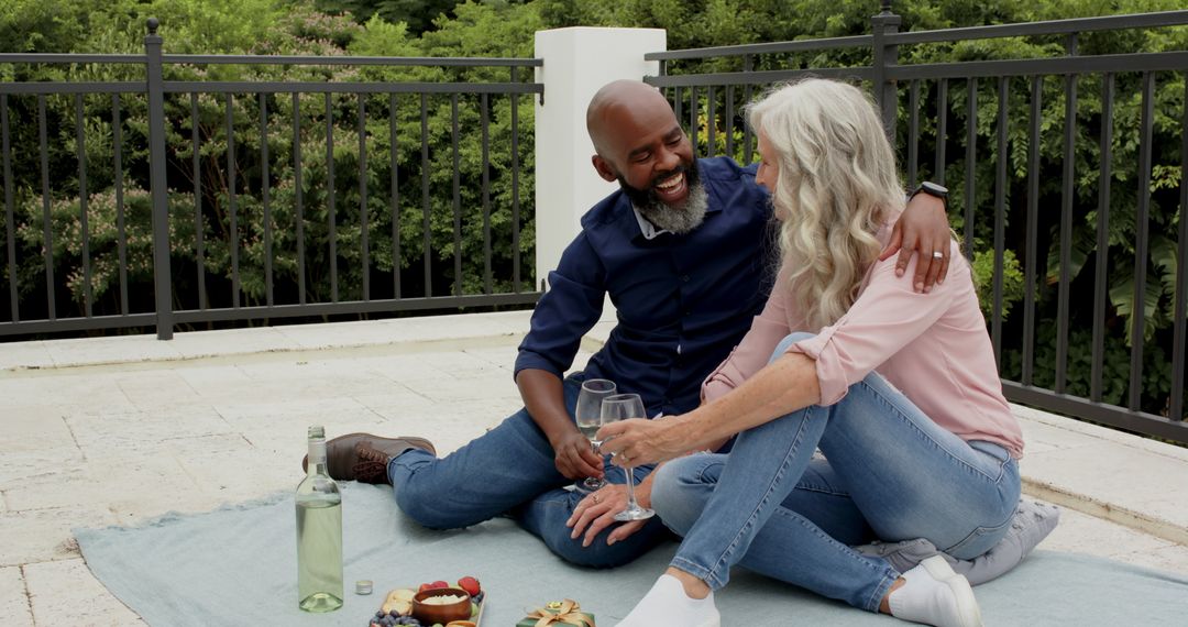 Smiling Couple Enjoying Wine and Snacks on Sunny Terrace Picnic