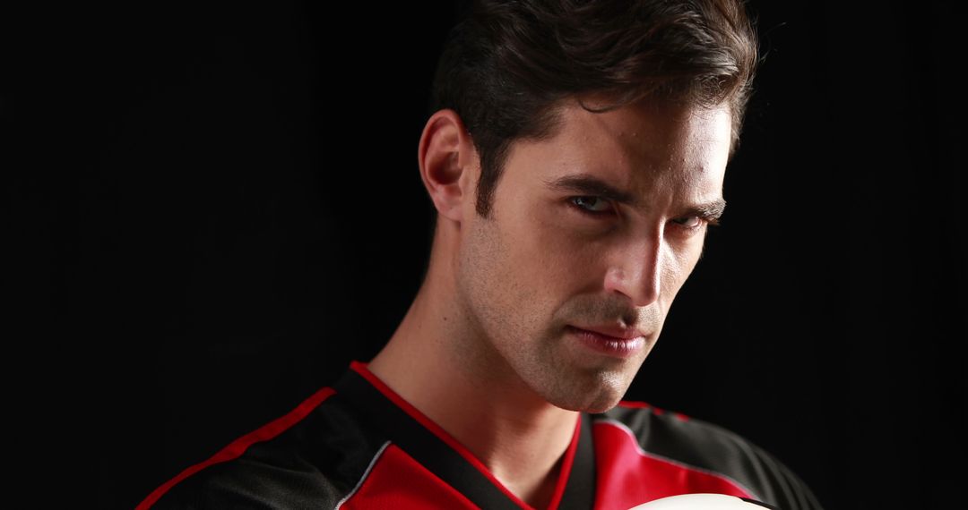 Intense Soccer Player Wearing Red and Black Jersey Holding Soccer Ball - Free Images, Stock Photos and Pictures on Pikwizard.com