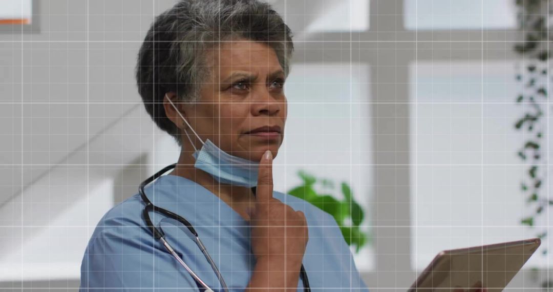 Senior Nurse Contemplating in Clinic With Tablet