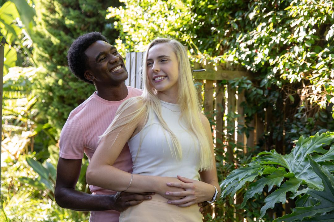 Caring Couple Embracing in Leafy Garden with Sunlit Smiles