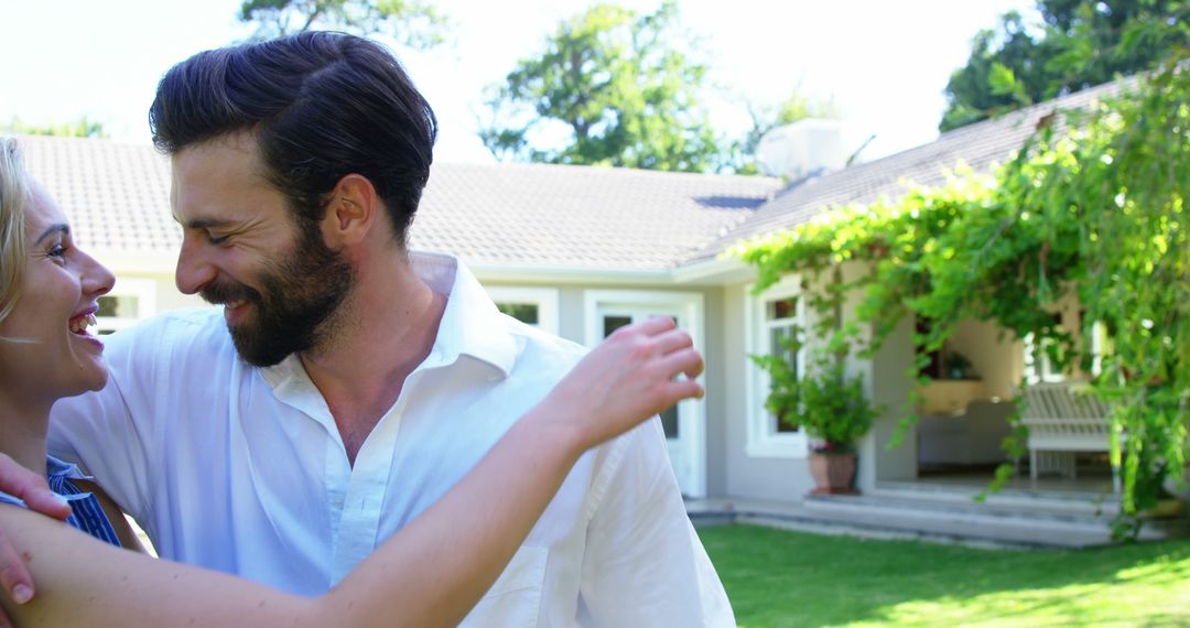 Cute couple smiling and holding each other in front of a house on a sunny day  - Free Images, Stock Photos and Pictures on Pikwizard.com