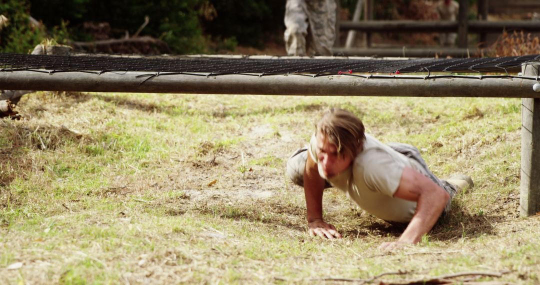 Determined Military Personnel Crawling Through Obstacle Course Challenge