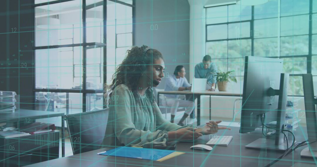 Headset Support Specialist Working at Desktop with Data Overlay in open-plan Modern Office