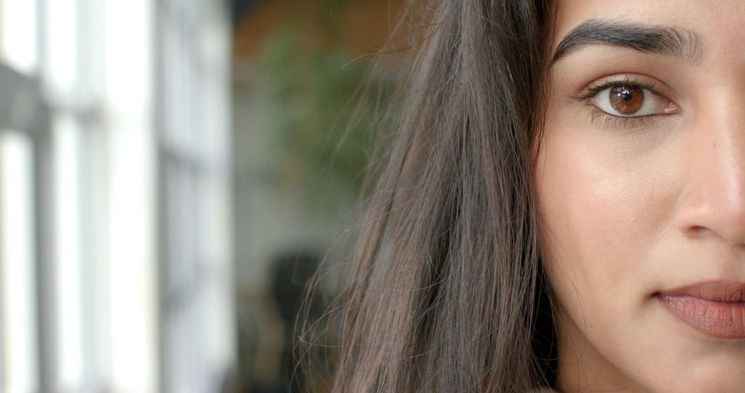 Closeup Indian woman gazing by multi-pane window with soft natural light and copy space