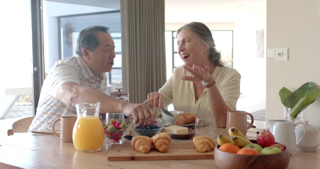 Senior Couple Enjoying Breakfast with Croissants and Fresh Fruit