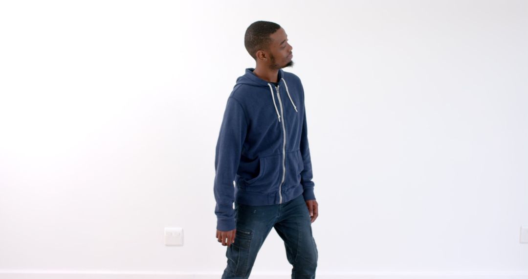 Young man wearing blue hoodie looking confident indoors