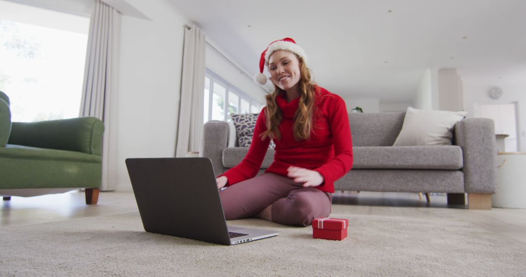 Woman with Santa hat video chatting on laptop in modern living room during Christmas season - Free Images, Stock Photos and Pictures on Pikwizard.com