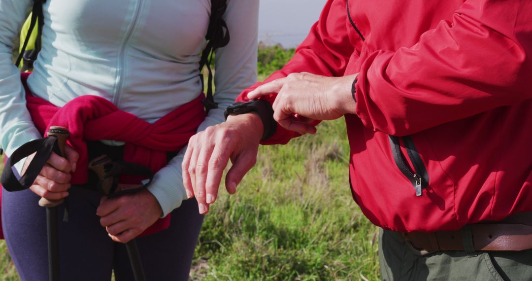 Senior Couple Using Smartwatch While Hiking in Mountains