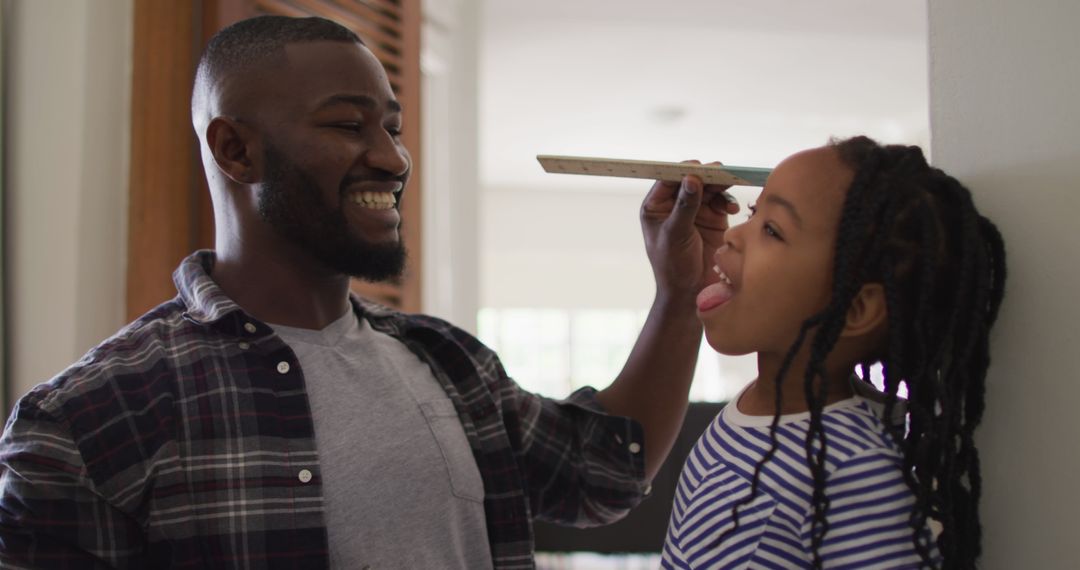 Father Measuring Daughter's Growth with Ruler at Home