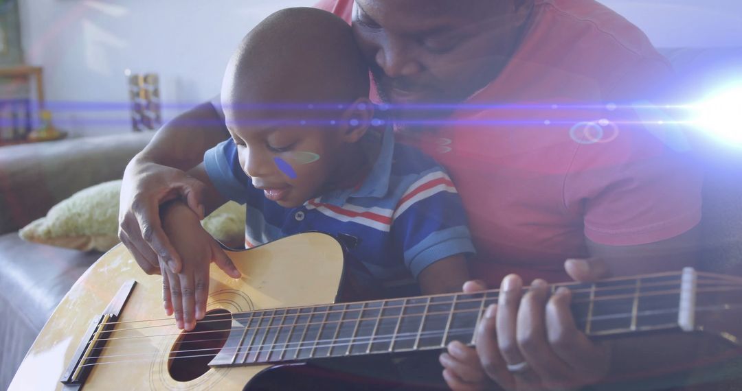 Father teaching son acoustic guitar on couch