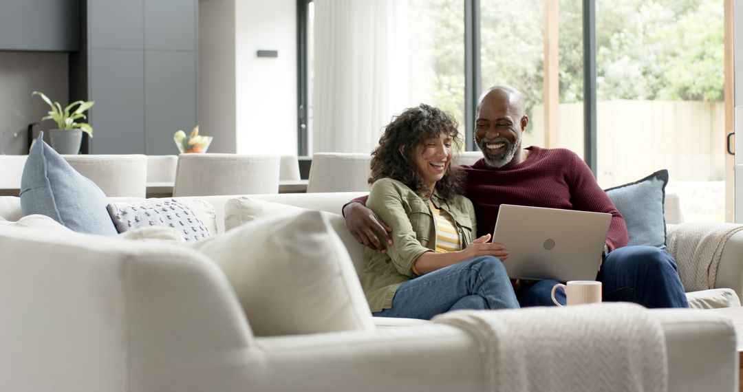Happy Couple Relaxing on Couch with Laptop at Home
