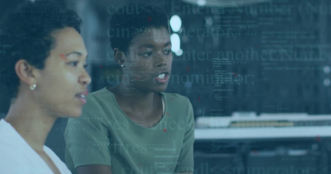 Women collaborating and reviewing code on glass partition in modern tech workspace