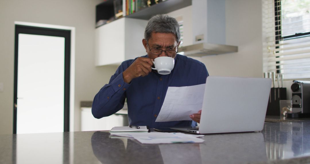 Senior Man Reviewing Documents at Home with Coffee and Laptop - Free Images, Stock Photos and Pictures on Pikwizard.com