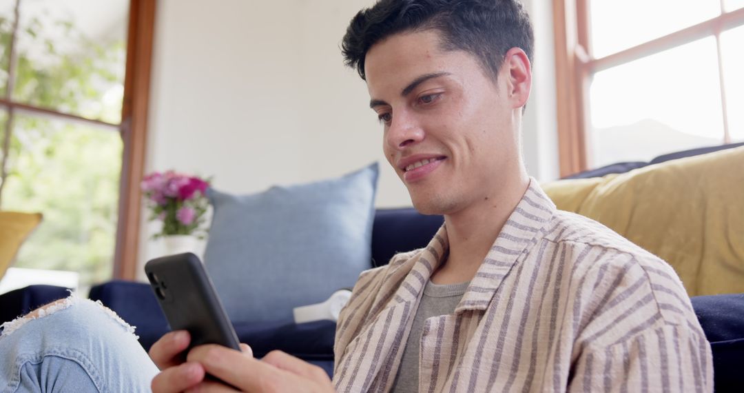 Smiling man using smartphone in cozy living room environment