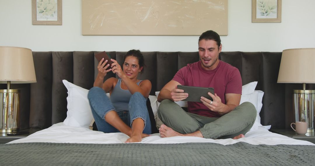Couple Discussing Plans Using Tablet on Bed at Home