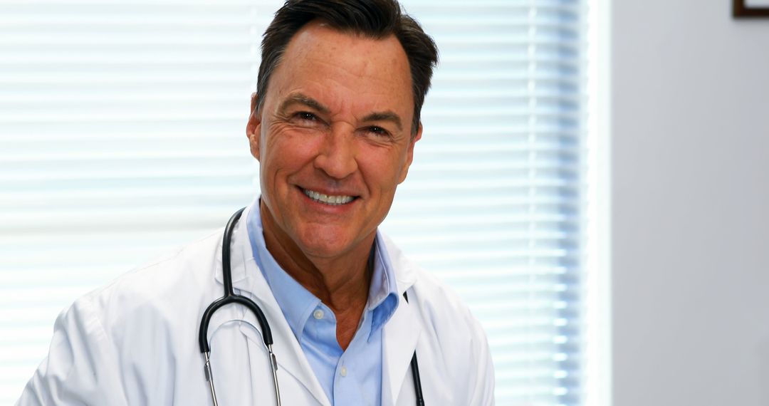 Smiling Mature Male Doctor in White Coat with Stethoscope in Modern Office - Free Images, Stock Photos and Pictures on Pikwizard.com