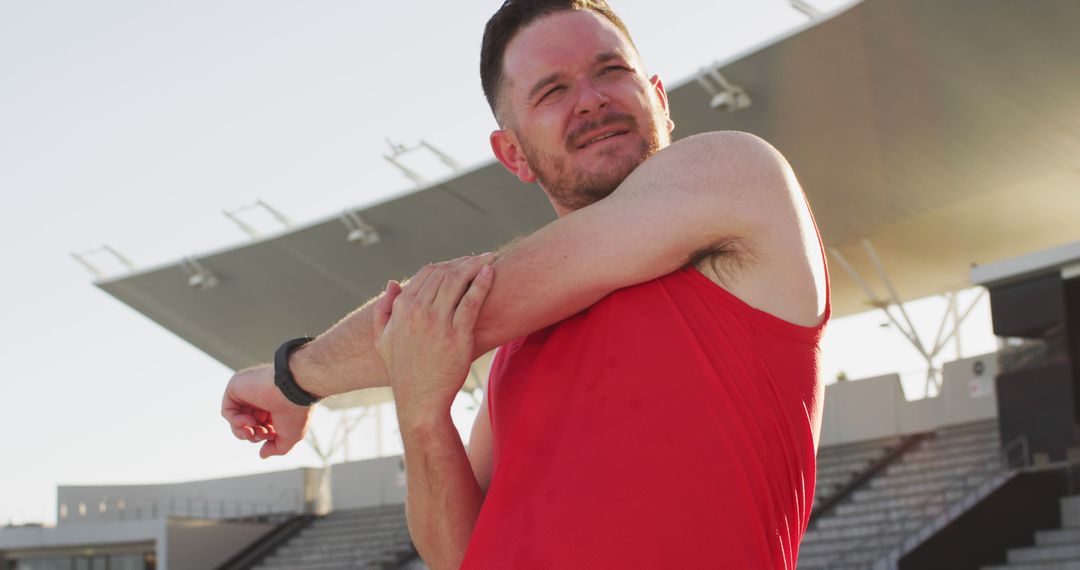 Man Stretching Arm in Outdoor Sports Stadium - Free Images, Stock Photos and Pictures on Pikwizard.com