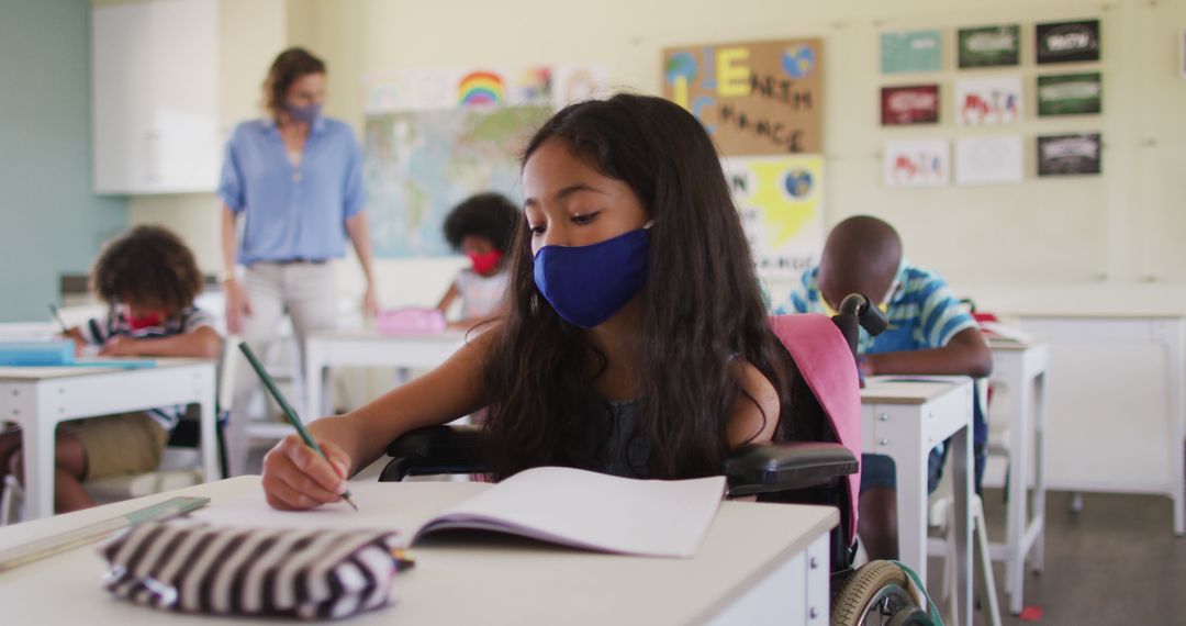 Young Student in Mask Writing in Classroom with Teacher Assisting in Background - Free Images, Stock Photos and Pictures on Pikwizard.com