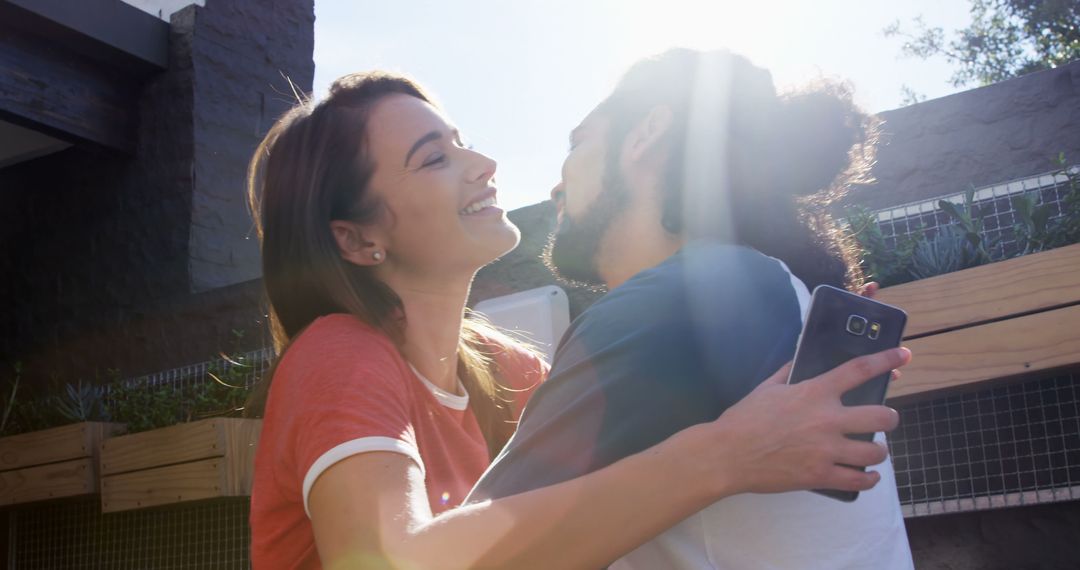 Couple Embracing Outdoors with Sunlight Streaming - Free Images, Stock Photos and Pictures on Pikwizard.com