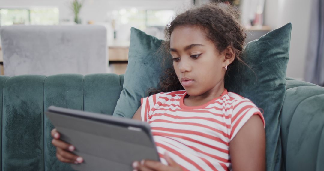 Young Girl Using Digital Tablet on Green Couch at Home - Free Images, Stock Photos and Pictures on Pikwizard.com