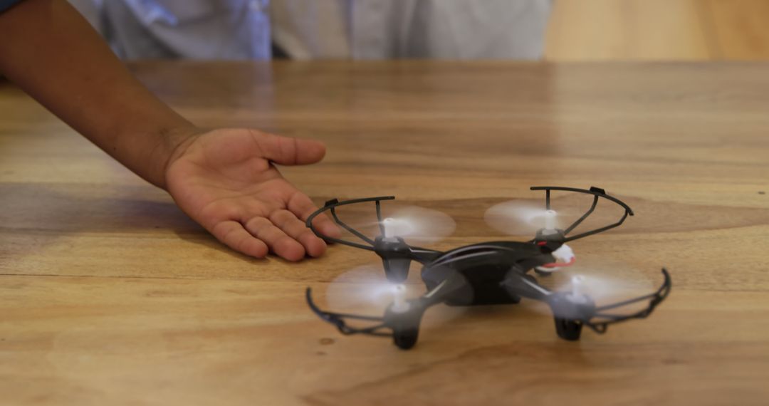 Person Controlling Small Toy Drone on Wooden Surface - Free Images, Stock Photos and Pictures on Pikwizard.com