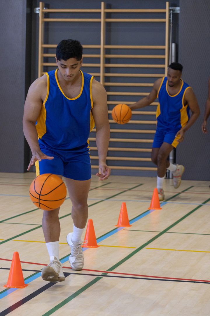 Basketball Players Dribbling Through Cones in Gym for Practice