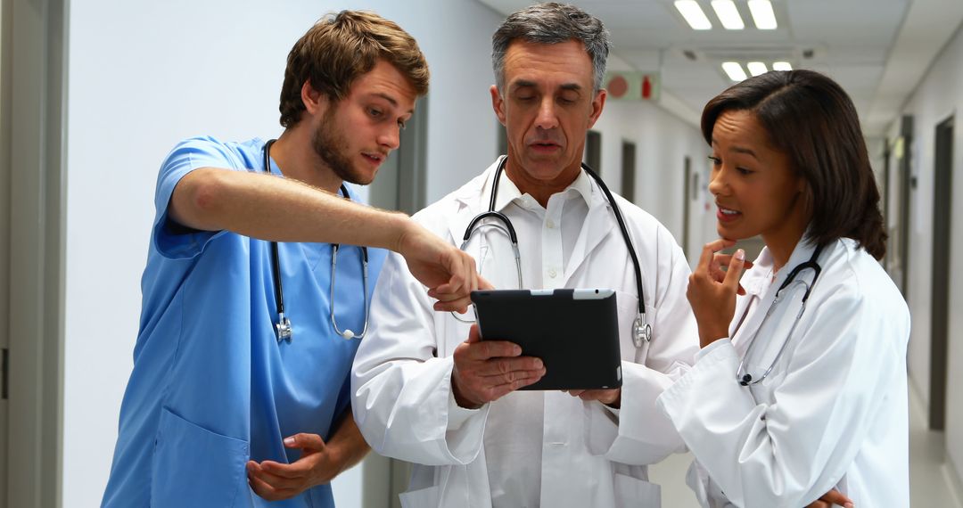 Medical Team Reviewing Patient Data on Tablet in Hospital Corridor - Free Images, Stock Photos and Pictures on Pikwizard.com